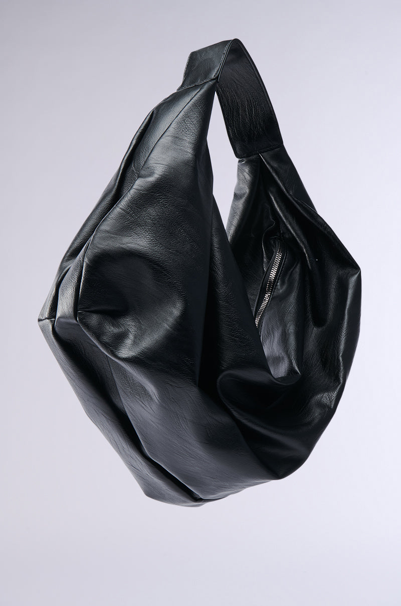 The EDITORIAL ONLY TOTE, a large black oversized hobo bag with a wide strap, hangs against a light gray background, highlighting its soft slouchy shape and textured finish—ideal for minimalist style. 3