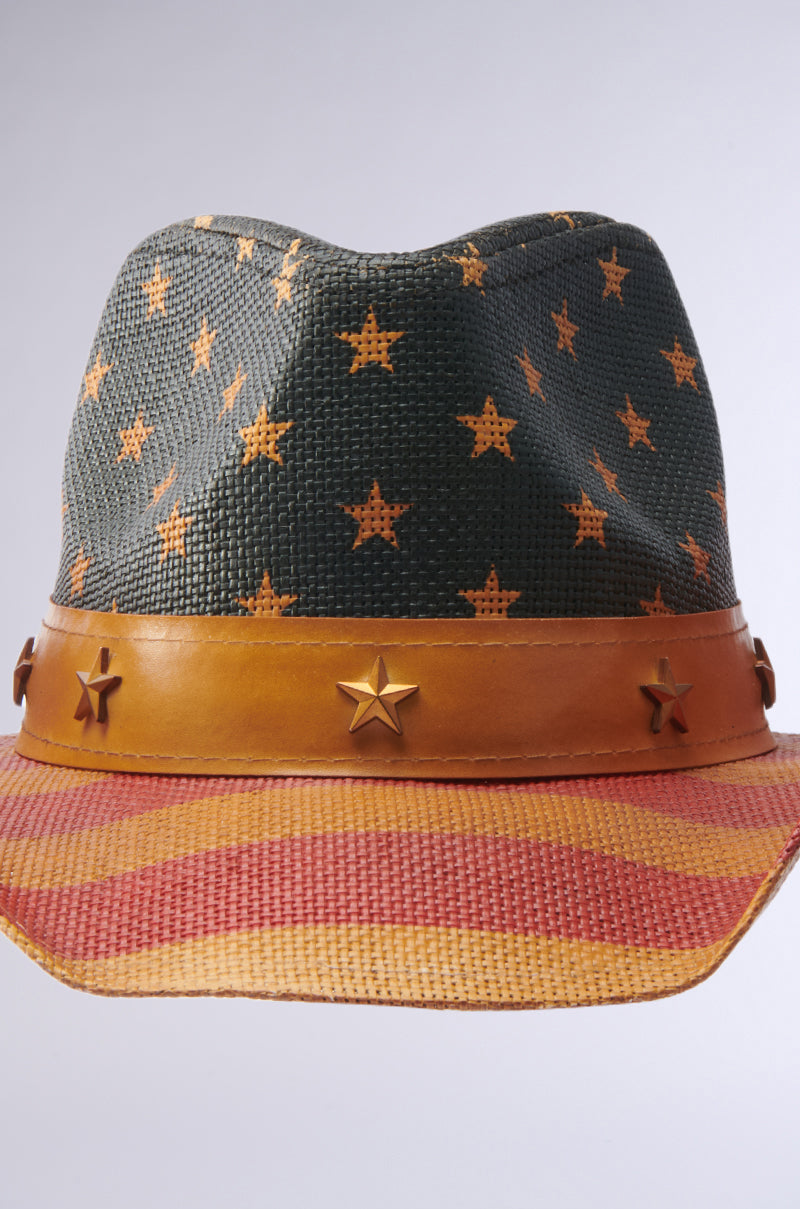 The AMERICAN DREAM COWBOY HAT features orange stars on a dark green crown, an orange band with star-shaped studs, and a brim with orange and red stripes—a bold update on the classic Patriotic Hat.