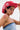 A person with short dark hair sports the ROSES ARE RED COWBOY HAT with white floral designs, a nose ring, and a strapless denim top. A bold maroon stripe tattoo accents their shoulder as they look confidently at the camera.