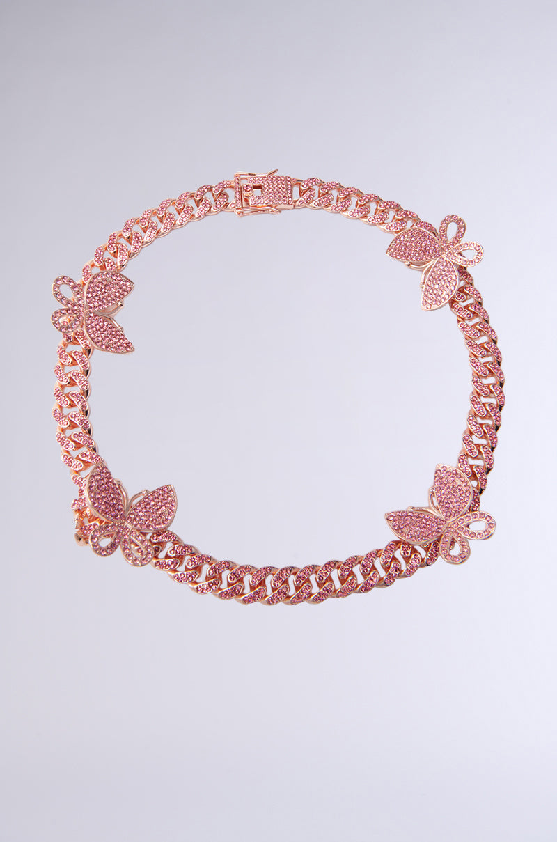 The FLY AWAY ICED OUT CHAIN, a rose gold necklace with butterfly-shaped embellishments set against a plain gray background, beautifully embodies elegance and charm.