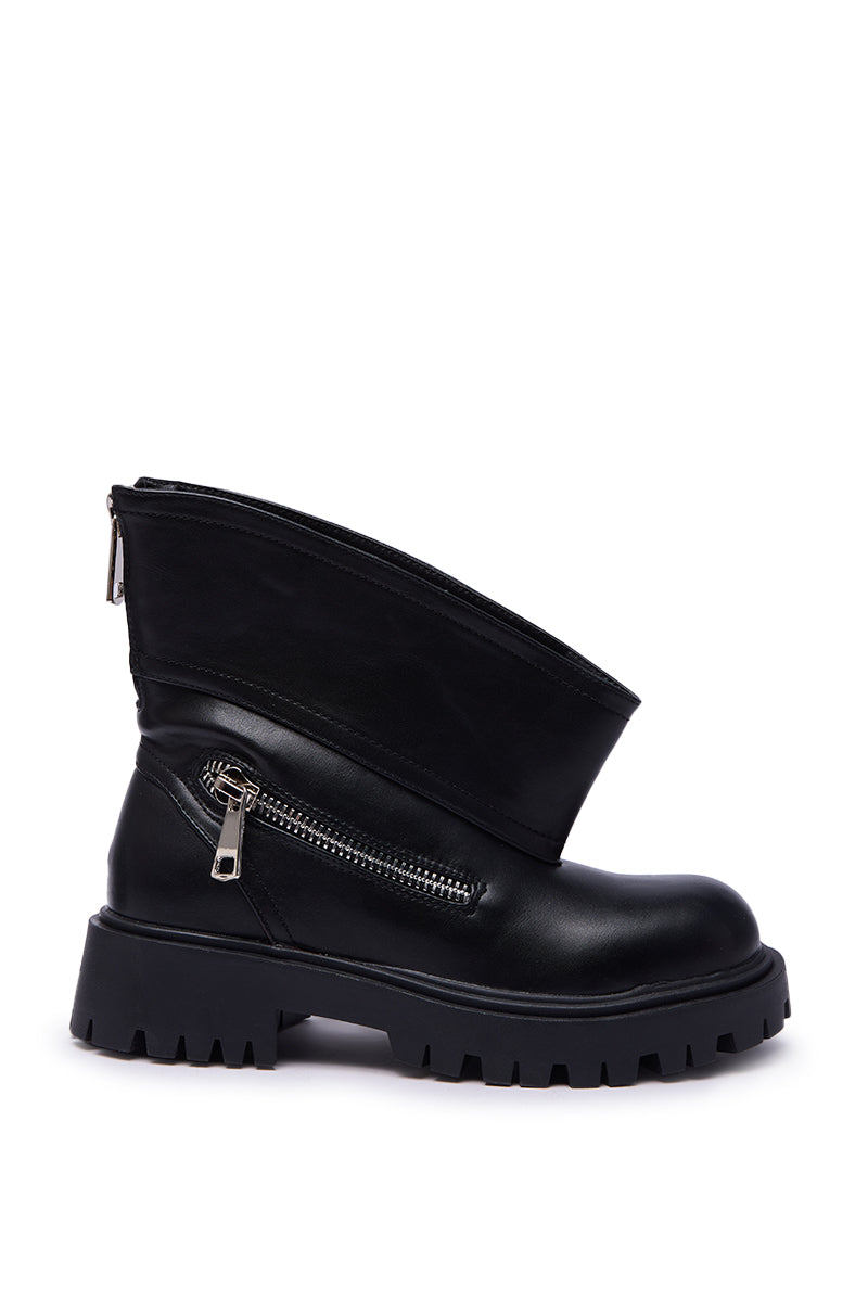 The AZALEA WANG MOHSEN BLACK COMBAT BOOTIE is a black faux leather combat boot with a rugged sole, asymmetrical folded-over shaft, decorative side zipper, and top edge zipper, shown on a white background.