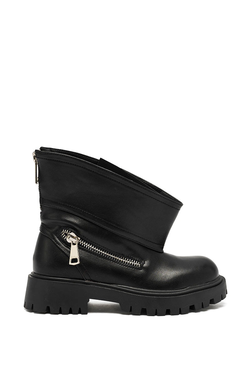 The AZALEA WANG MOHSEN BLACK COMBAT BOOTIE features black faux leather, a chunky lug sole, side zipper, and an asymmetrical overlapping flap for a bold combat-inspired style.