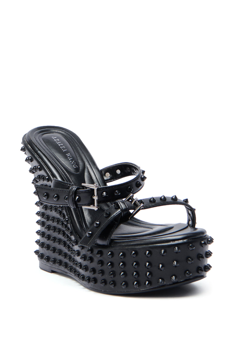 The AZALEA WANG MORITZ BLACK SPIKEY WEDGE SANDAL features black spikes on the straps, platform, and wedge heel, an open toe, side buckle, and a Comfort Cushion insole—for edgy punk-glam style with all-day comfort.