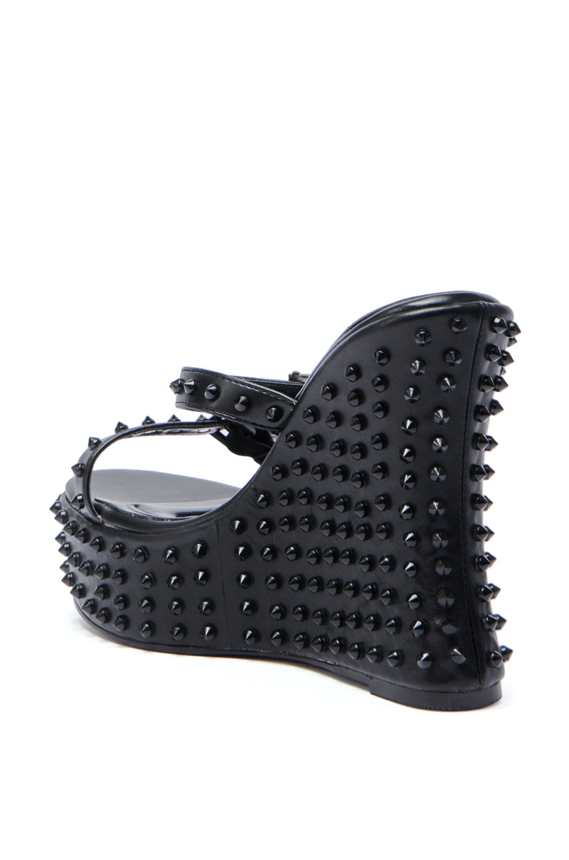 The AZALEA WANG MORITZ BLACK SPIKEY WEDGE SANDAL features an ankle strap and is covered in black studs, giving it a bold punk-glam vibe.