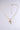 The CROSSES NECKLACE is a faux gold piece with a delicate chain of small links, featuring a rhinestone cross pendant adorned with white stones. It includes an adjustable length, extension chain, and clasp, all on a plain light gray background.