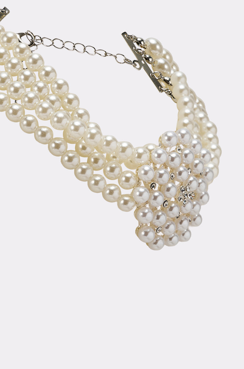 The TRULY PEARL CHOKER features three rows of faux pearls with a silver clasp and a central floral cluster adorned with rhinestones, creating an elegant multi-strand necklace. 5