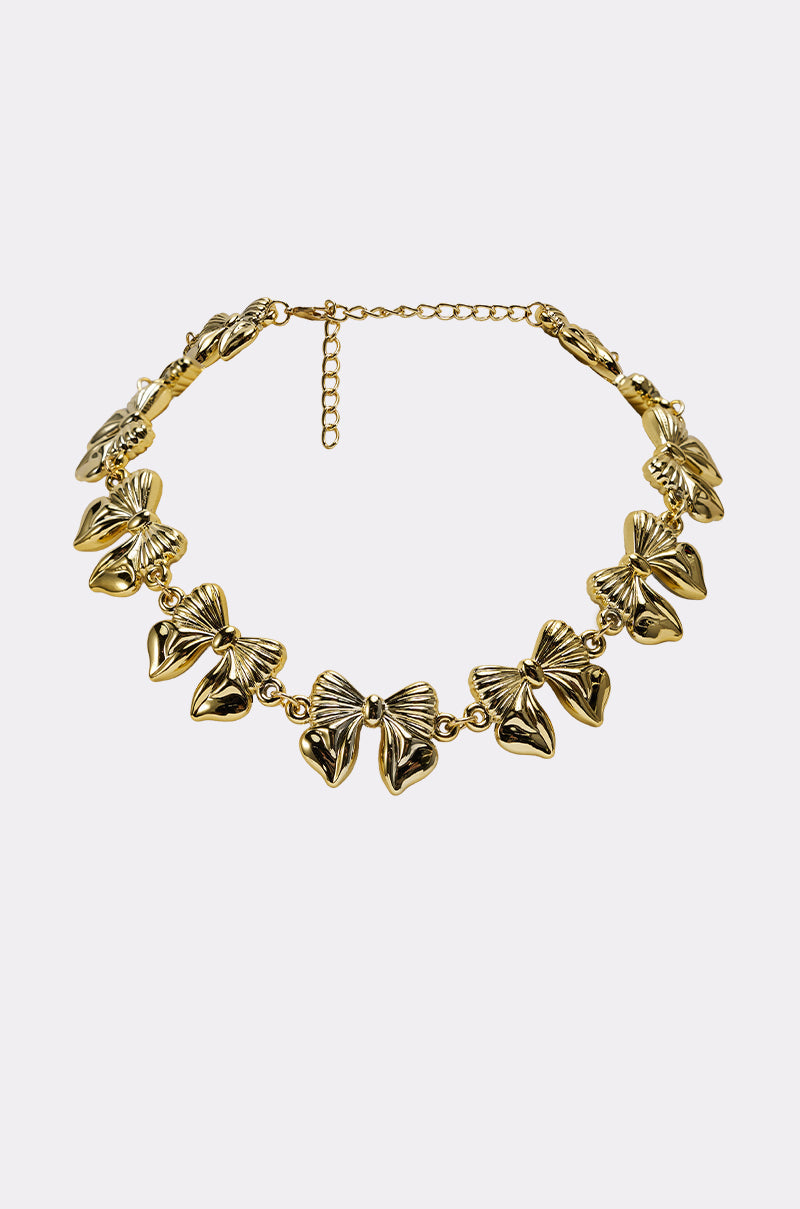 The AKIRA Label BOW NECKLACE is a gold-tone piece featuring multiple butterfly-shaped charms linked together with an adjustable chain clasp, shown elegantly against a plain light background. 0