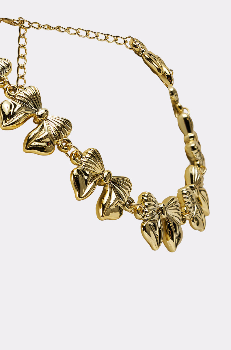 The BOW NECKLACE features multiple shiny gold-tone butterfly charms linked together and an adjustable clasp, displayed against a plain light background. 3