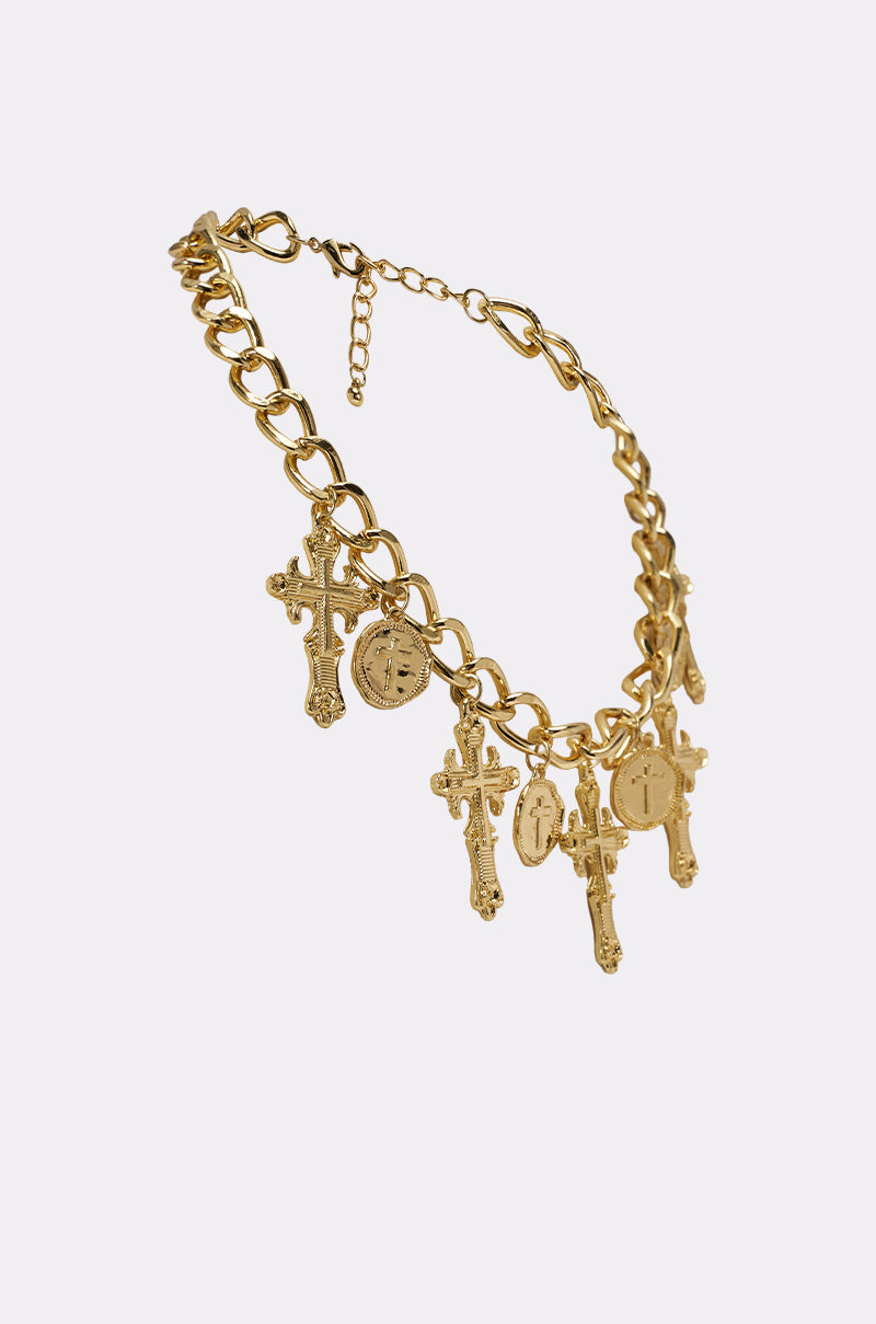 The CHARMED LIFE NECKLACE is a gold cross necklace with multiple cross and round medallion charms on a chunky chain, displayed on a light background. 4
