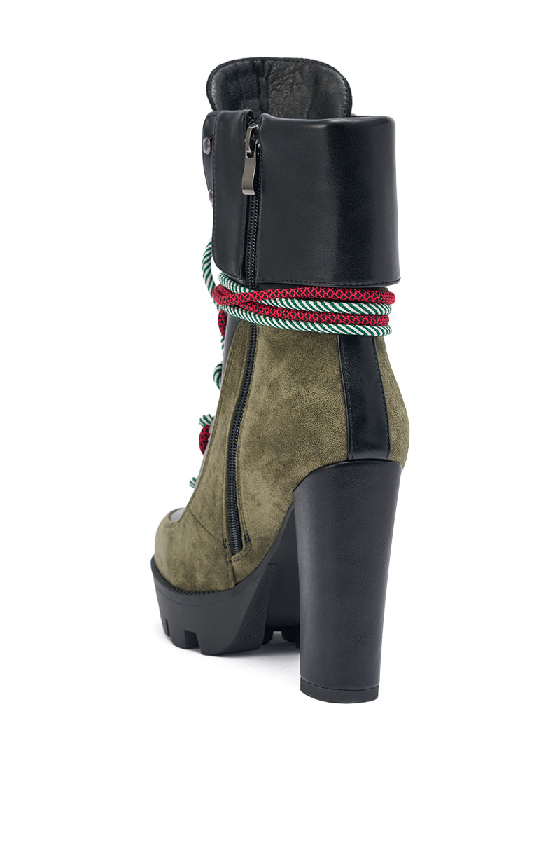 The AKIRA GOLD MUFFLER GREENMULTI CHUNKY HEEL BOOTIE features olive green suede, black leather accents, colorful striped laces, side zipper, and a thick black heel—shown from the back for a stylish faux suede boot look.