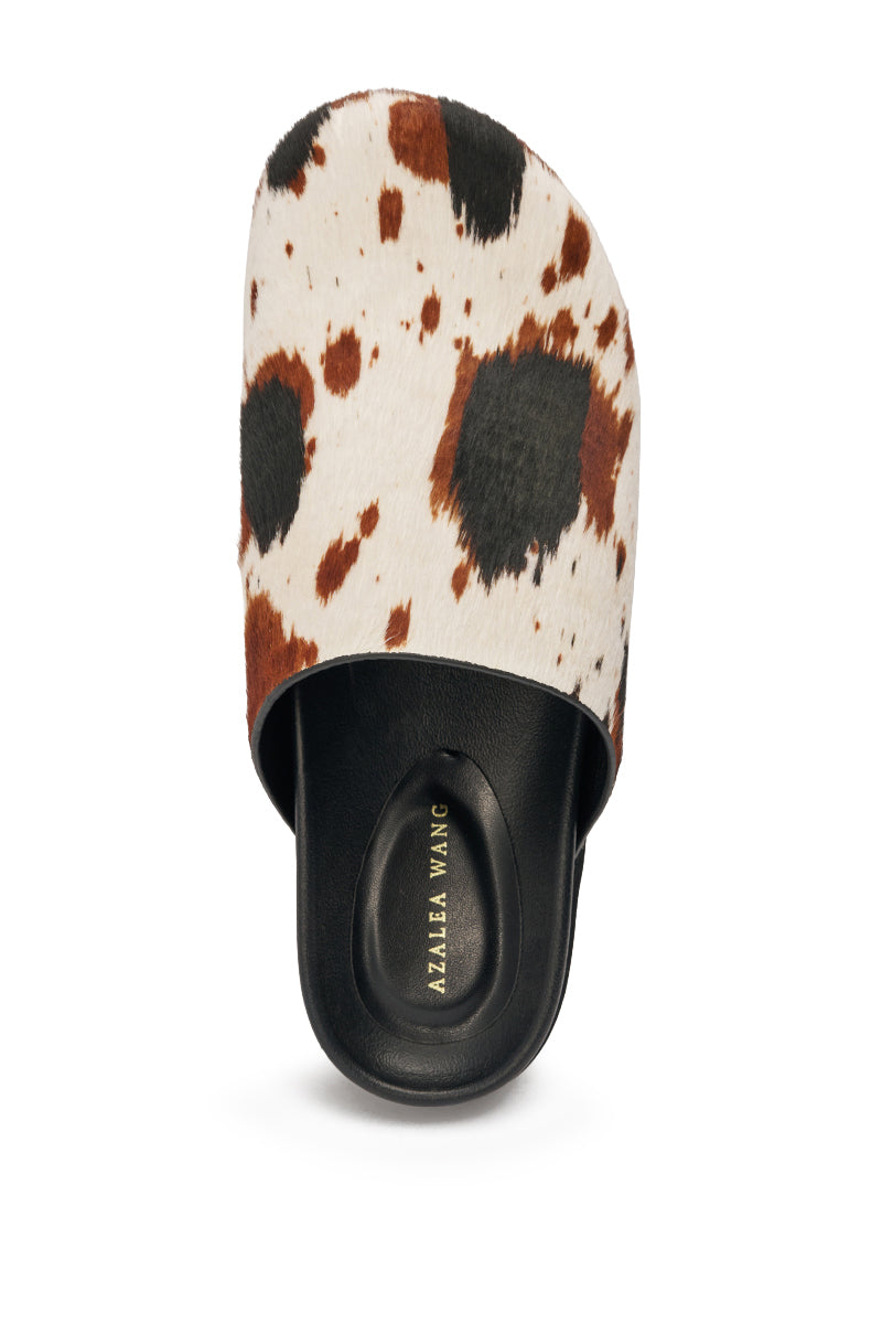 The AZALEA WANG MUKEY COW PRINT CALF HAIR FLAT is a slip-on mule with a black sole, wide brown and black cow print calf hair upper, and a black insole featuring the "Alaïa Wang" logo in gold. 3