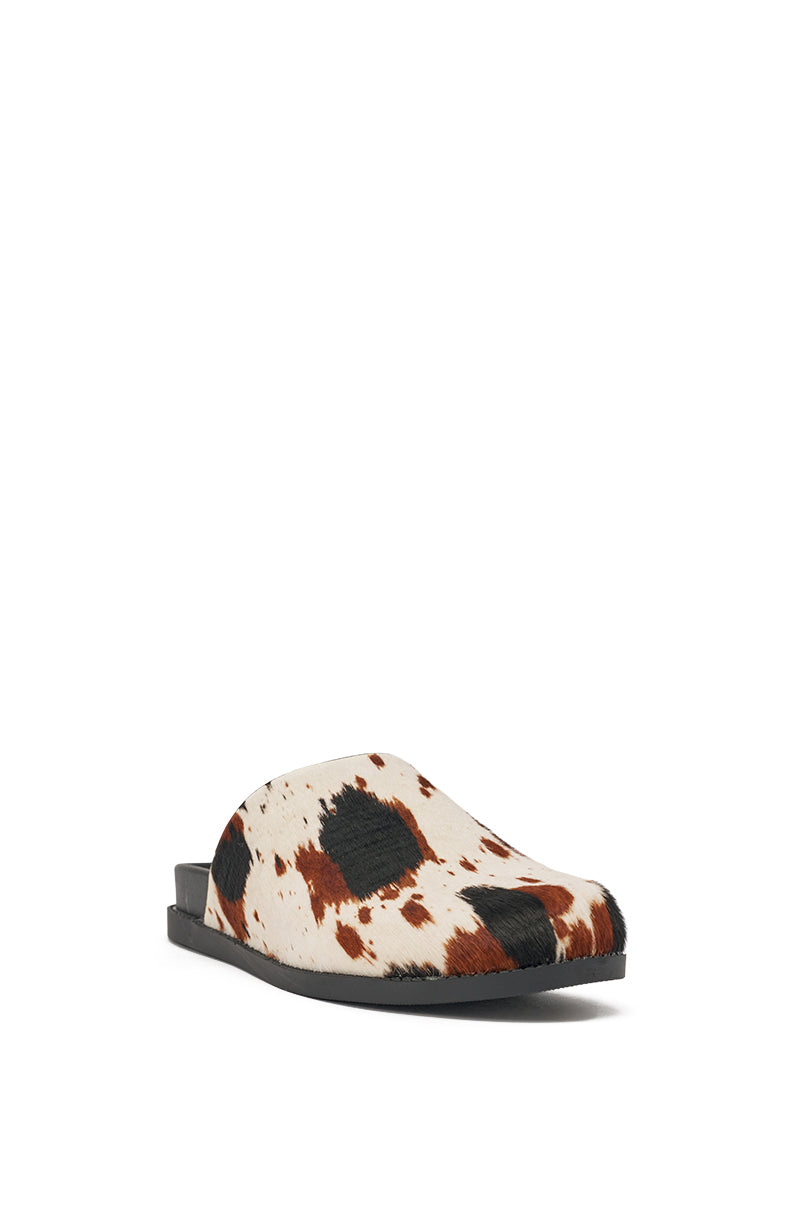 The AZALEA WANG MUKEY COW PRINT CALF HAIR FLAT is a slip-on mule with a black flat sole and a genuine calf hair upper in white, brown, and black cow print, shown here against a white background. 4
