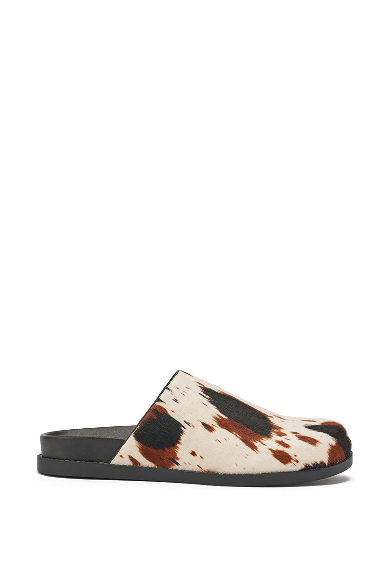 The AZALEA WANG MUKEY COW PRINT CALF HAIR FLAT is a slip-on mule with a black sole and genuine calf hair upper, showcasing a bold brown and black cow print pattern on a white background. 5
