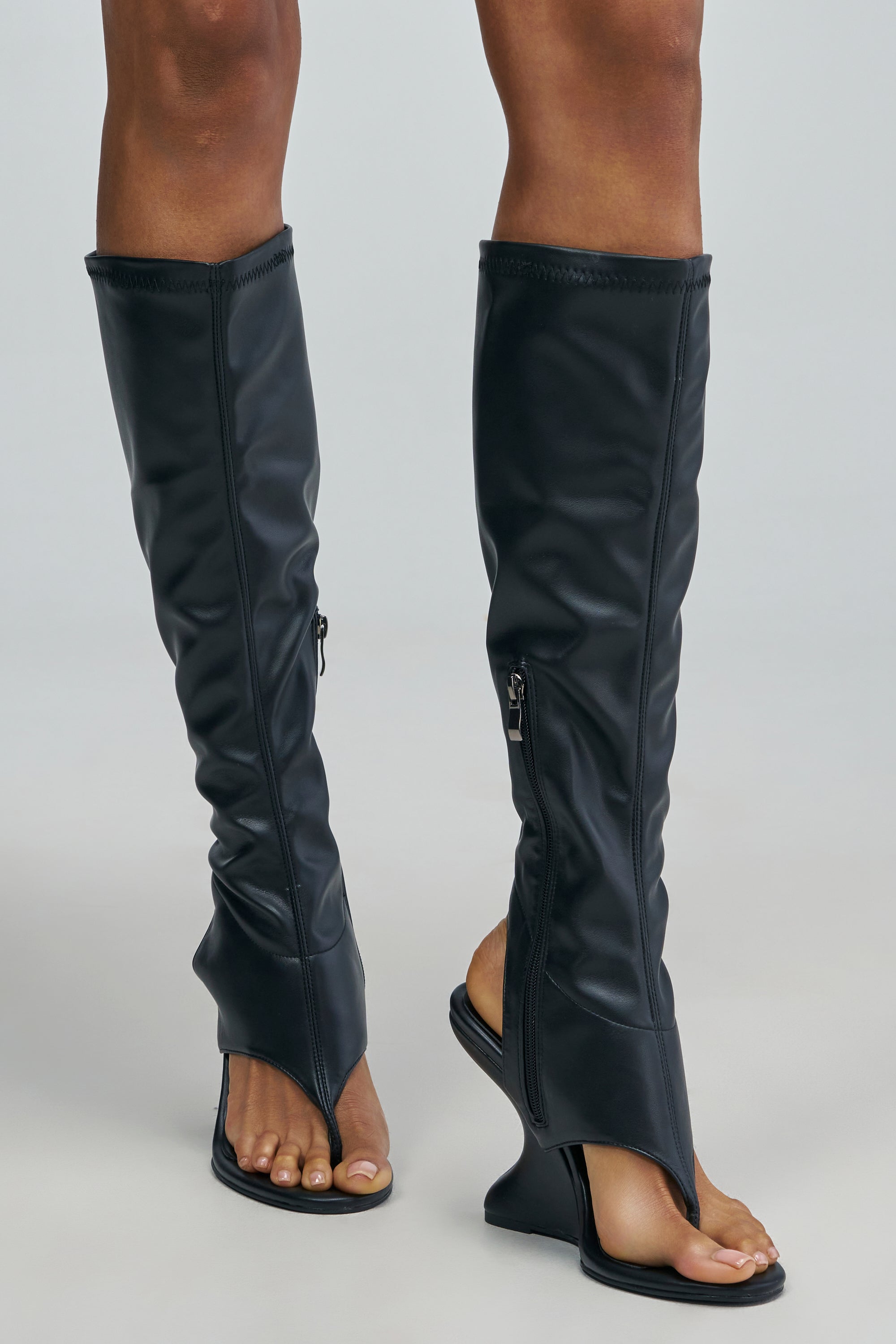 AZALEA WANG MUTED BLACK GLADIATOR WEDGE SANDALS in black faux leather, featuring a knee-high design, a thong-style toe post, and side zippers.