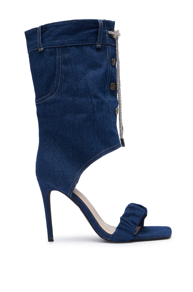 The AZALEA WANG MYKEL DENIM GLADIATOR SANDAL WITH RHINESTONE LACE mimics the look of denim jeans with its medium wash blue denim fabric, button detailing, peep toe, and silver rhinestone shoelace tie. Its stiletto heel and ankle cut-out reveal your foot, giving this edgy design the unmistakable allure of a denim gladiator sandal.