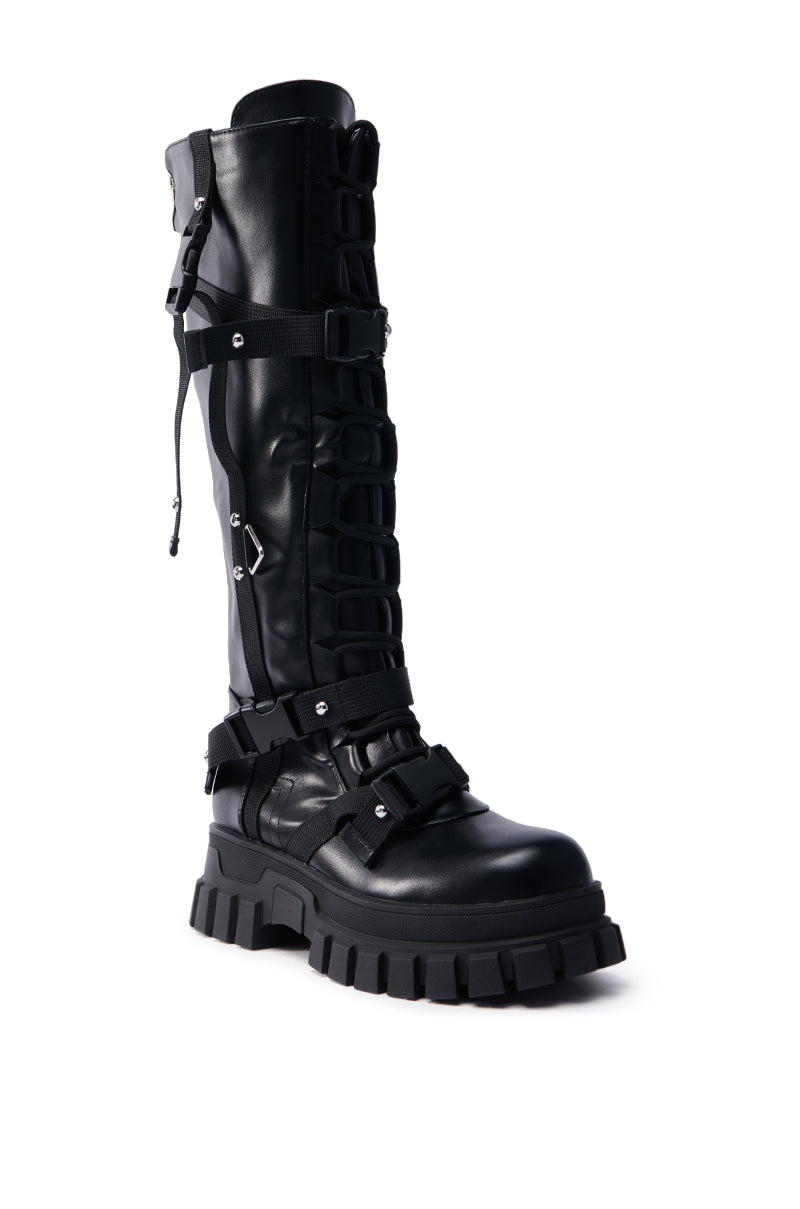 Introducing the AZALEA WANG MYRON BLACK BOOT, a knee-high black faux leather combat boot featuring a chunky treaded sole with multiple metallic fastened straps. These boots offer a rugged and edgy design, perfect for stylish and functional wear.