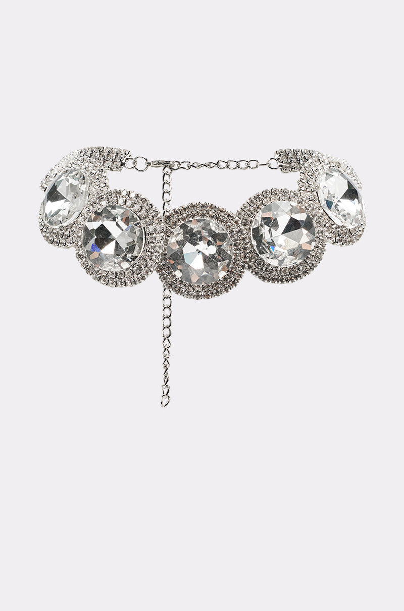 The AT THE BALL CHOKER is a silver crystal necklace with five large round clear gemstones, each framed by smaller rhinestones and linked by a metal chain with an adjustable clasp—perfect for eveningwear. 0