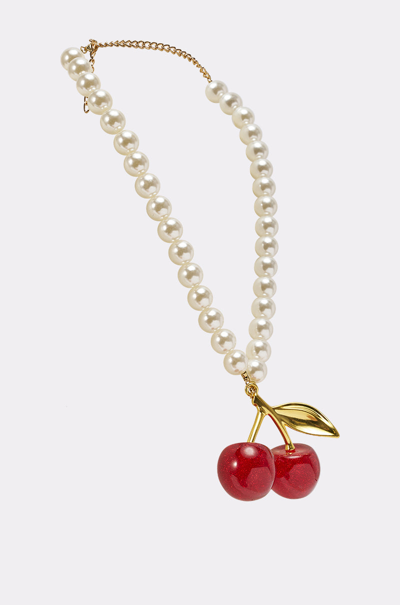 The POP MINE NECKLACE is a playful jewelry piece with round white pearls, a gold chain clasp, and a pendant of two glossy red cherries with a gold leaf—an eye-catching accessory for any outfit. 2