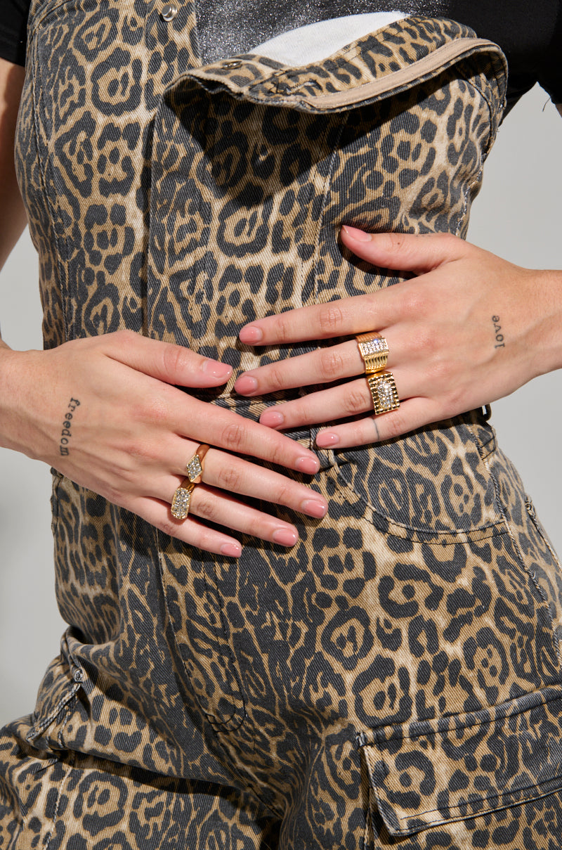 Close-up of a person exuding fierce energy in the FIERCE ENERGY ONLY LEOPARD JUMPSUIT, flaunting hands adorned with multiple gold rings. The person's nails are painted black, and small tattoos embellish their fingers.