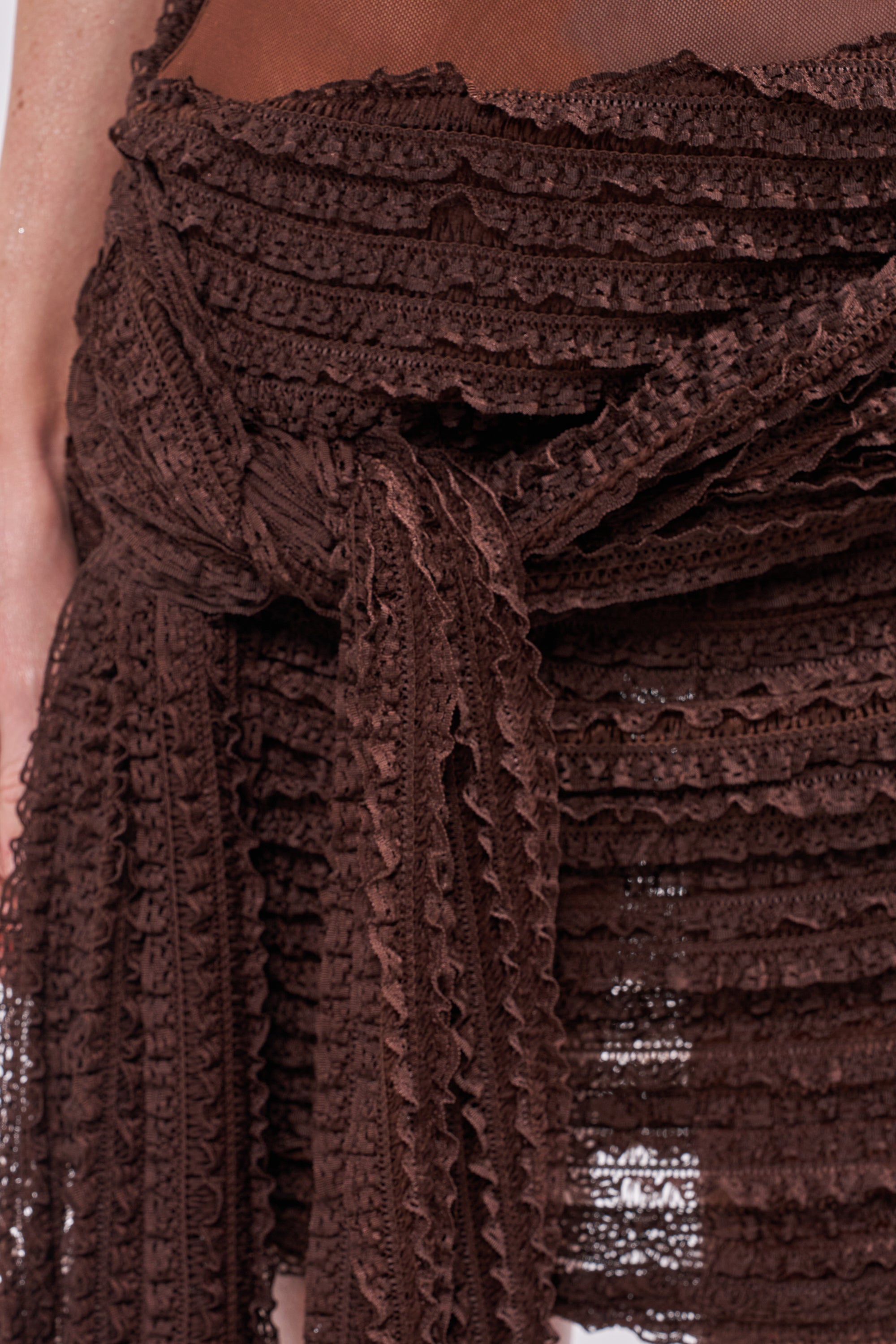 Close-up of the SWEET TALK STRAPLESS MINI DRESS: a brown crochet skirt with layered ruffles, tied waist, and semi-sheer flirty texture—ideal for summer vacations or layering over your favorite mini dress. 5