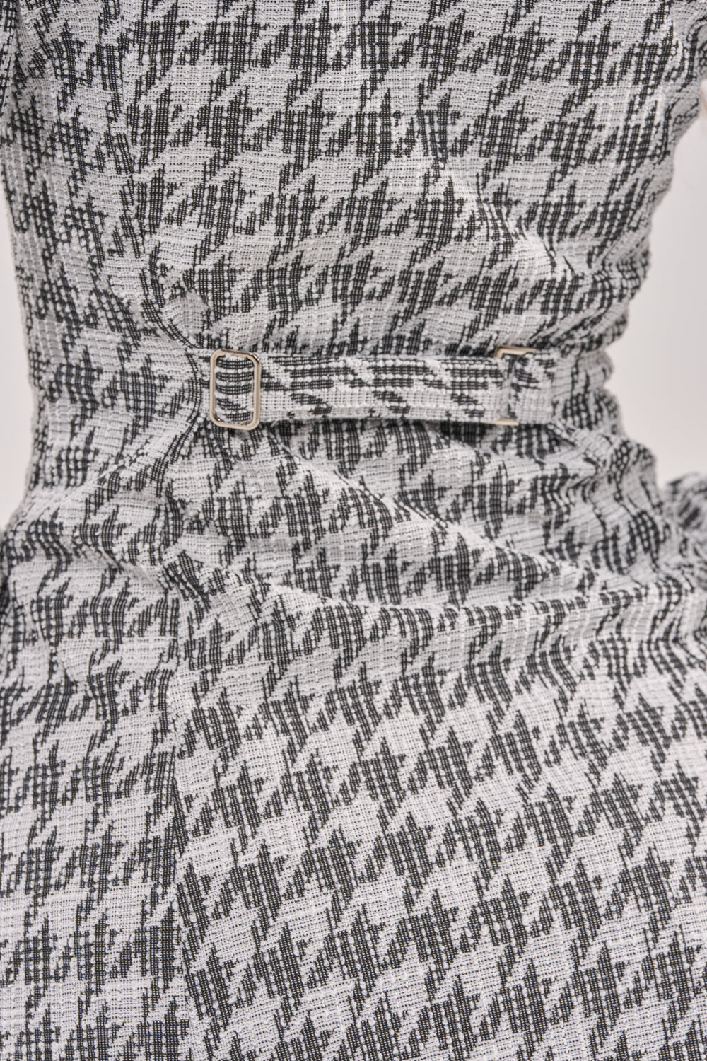 Close-up of the TALIA TWEED LONG SLEEVE COLLARED DRESS, showcasing its black and white houndstooth pattern, cinched waist, and small silver buckle detail. 8