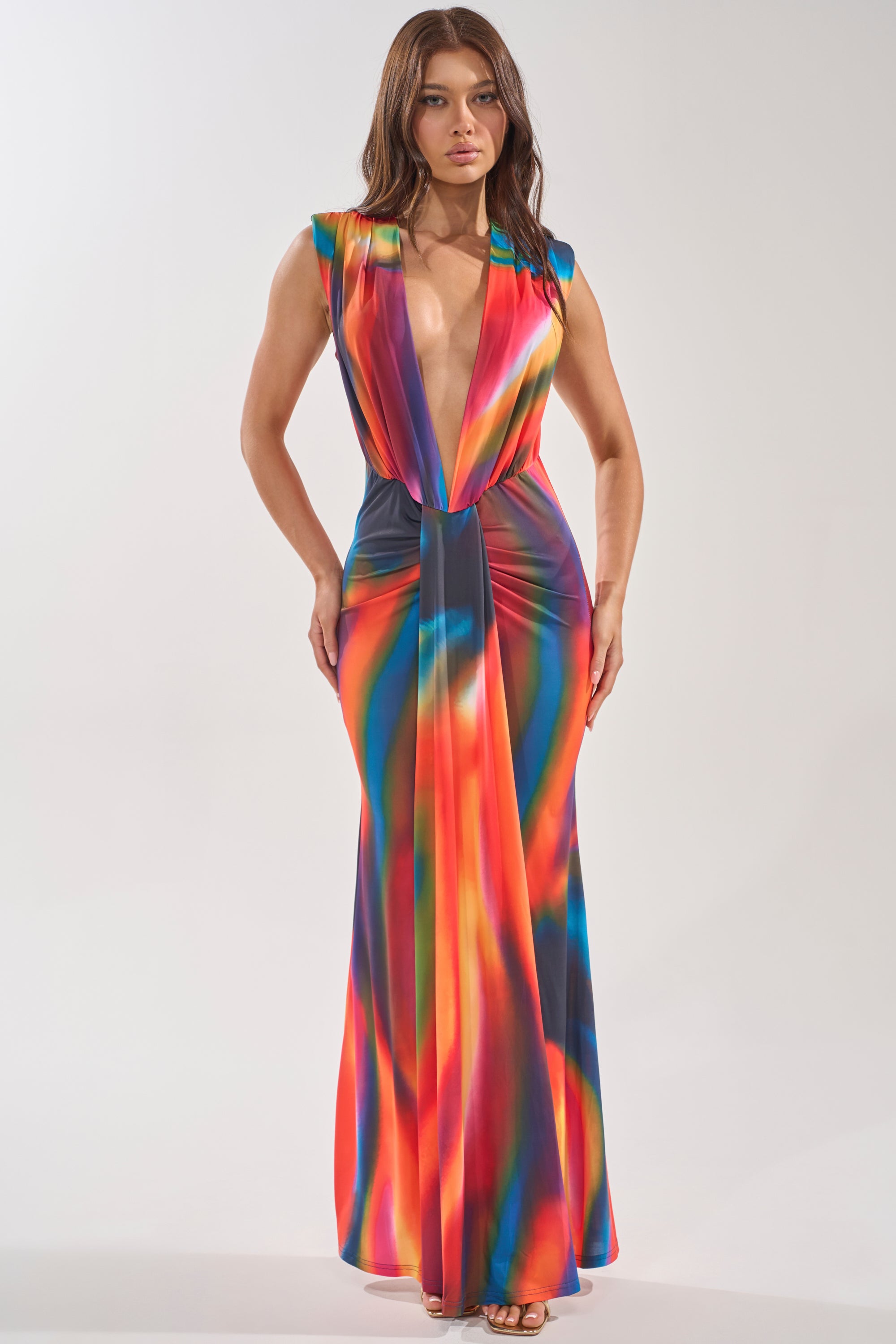 A woman stands facing forward against a plain background, wearing the COLOR ME IMPRESSED MAXI DRESS featuring an abstract print and a plunging neckline. 0