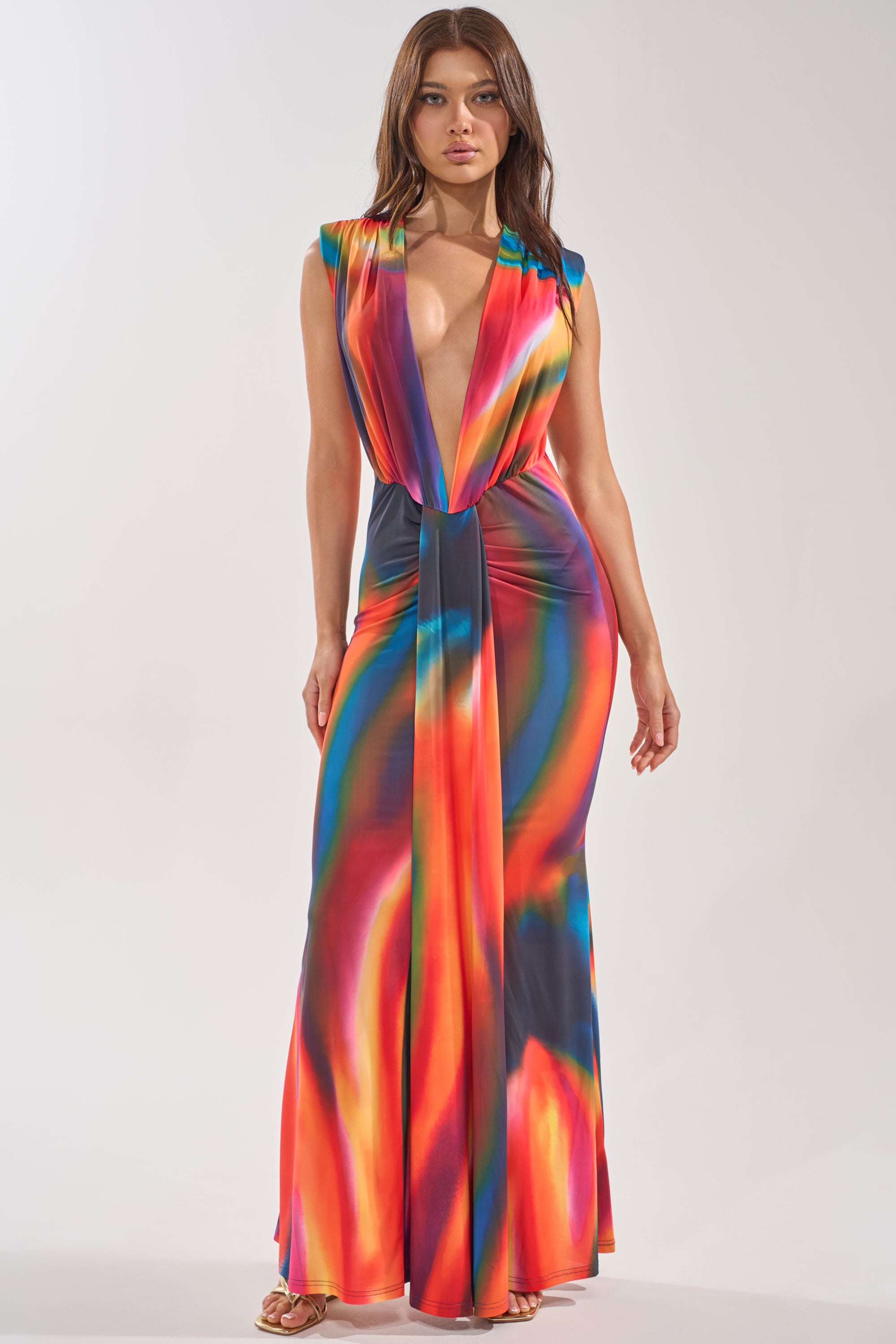A woman wears the COLOR ME IMPRESSED MAXI DRESS—a sleeveless, multicolor maxi with a deep V-neck, knotted waist detail, and watercolor-inspired pattern—paired with strappy sandals. 1