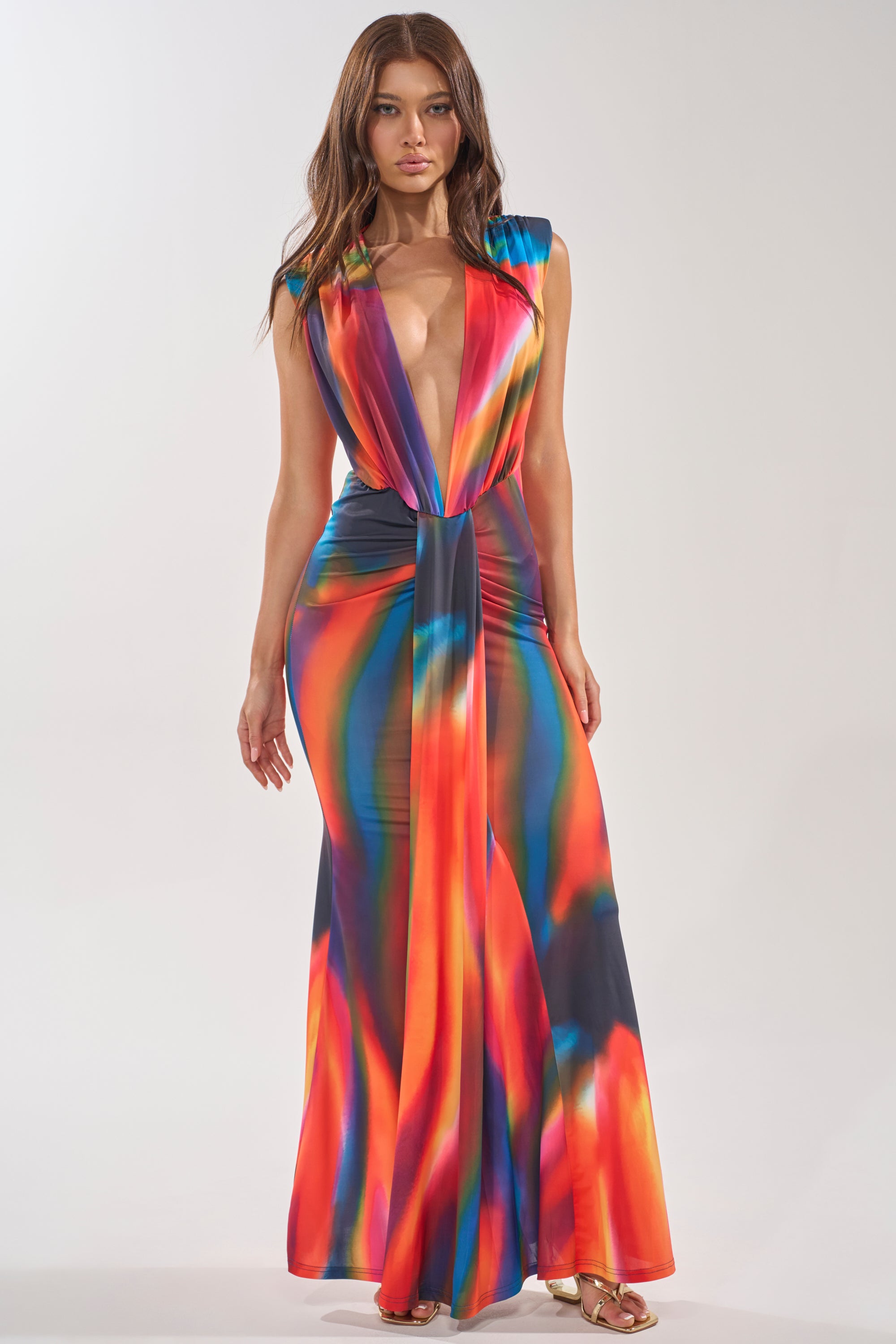 A woman models the COLOR ME IMPRESSED MAXI DRESS, a sleeveless maxi with a deep plunging neckline and vibrant watercolor print, against a plain background. 2