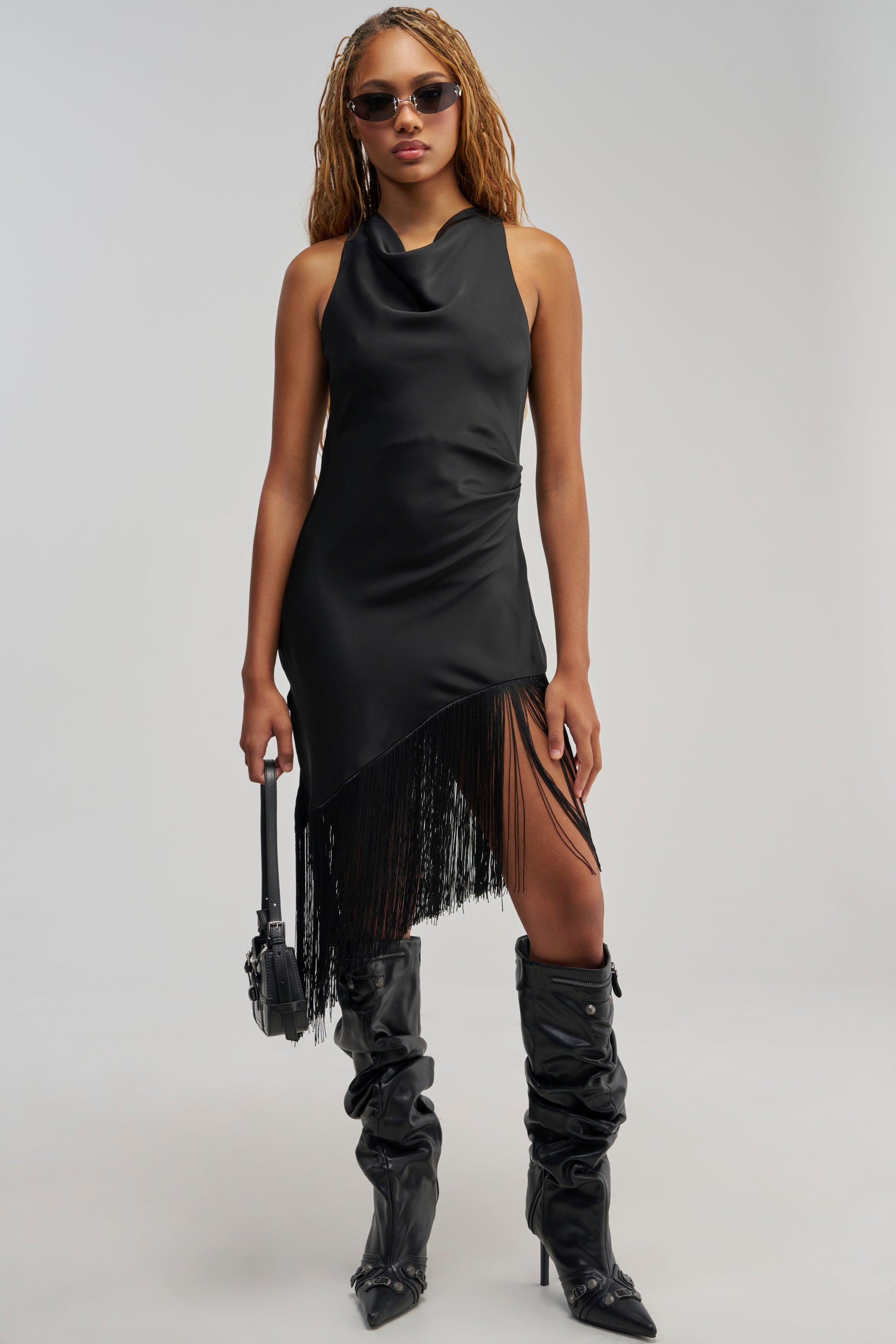 Dressed in the GRAND REVEAL FRINGE MIDI DRESS paired with tall black boots, sunglasses, and a sleek black handbag, this look exudes effortless chic—ideal for evening events or as a wedding guest ensemble.