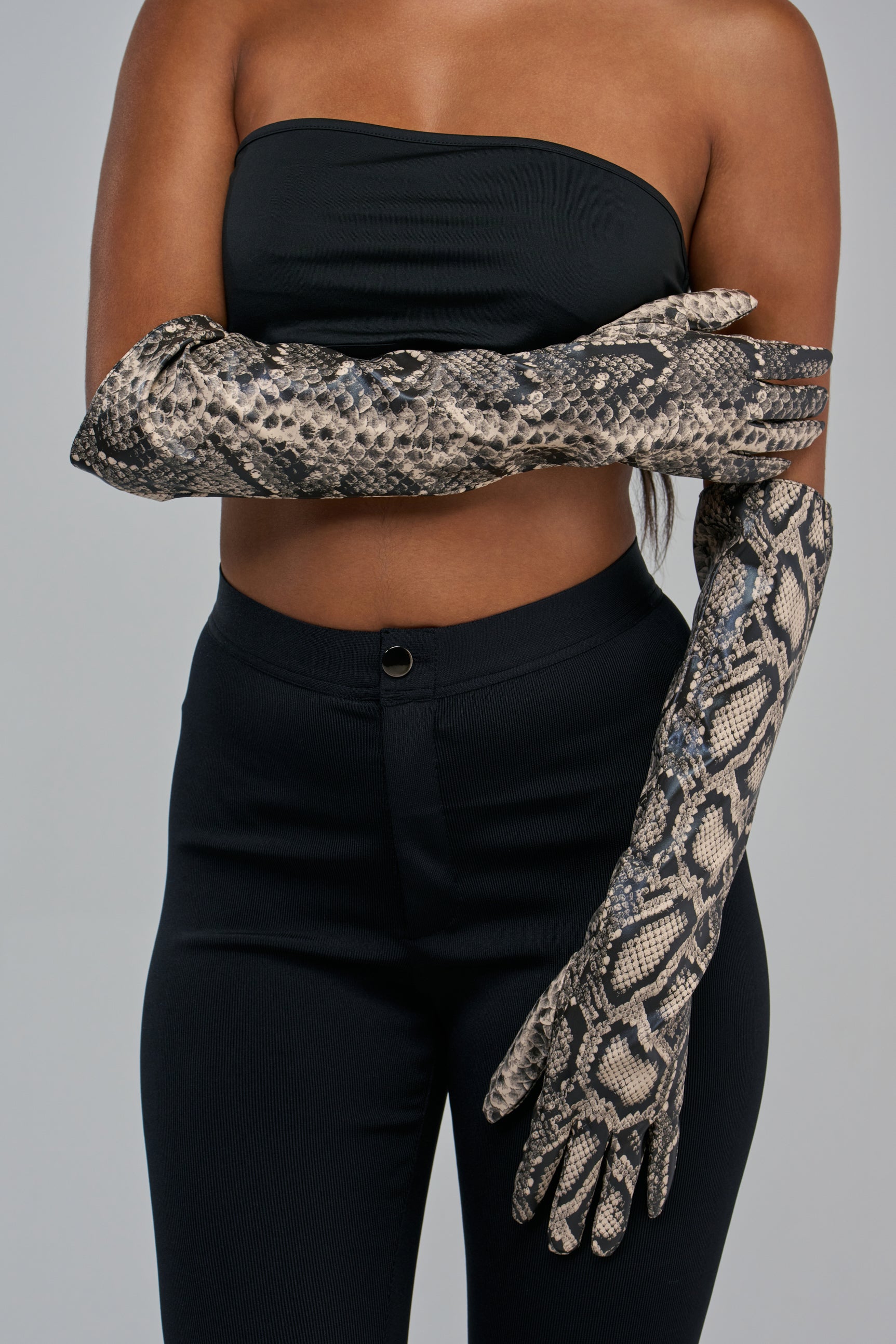 A person wearing SERPENT BEHAVIOR FAUX LEATHER GLOVES, which are elbow-length with a grey and black snakeskin pattern.
