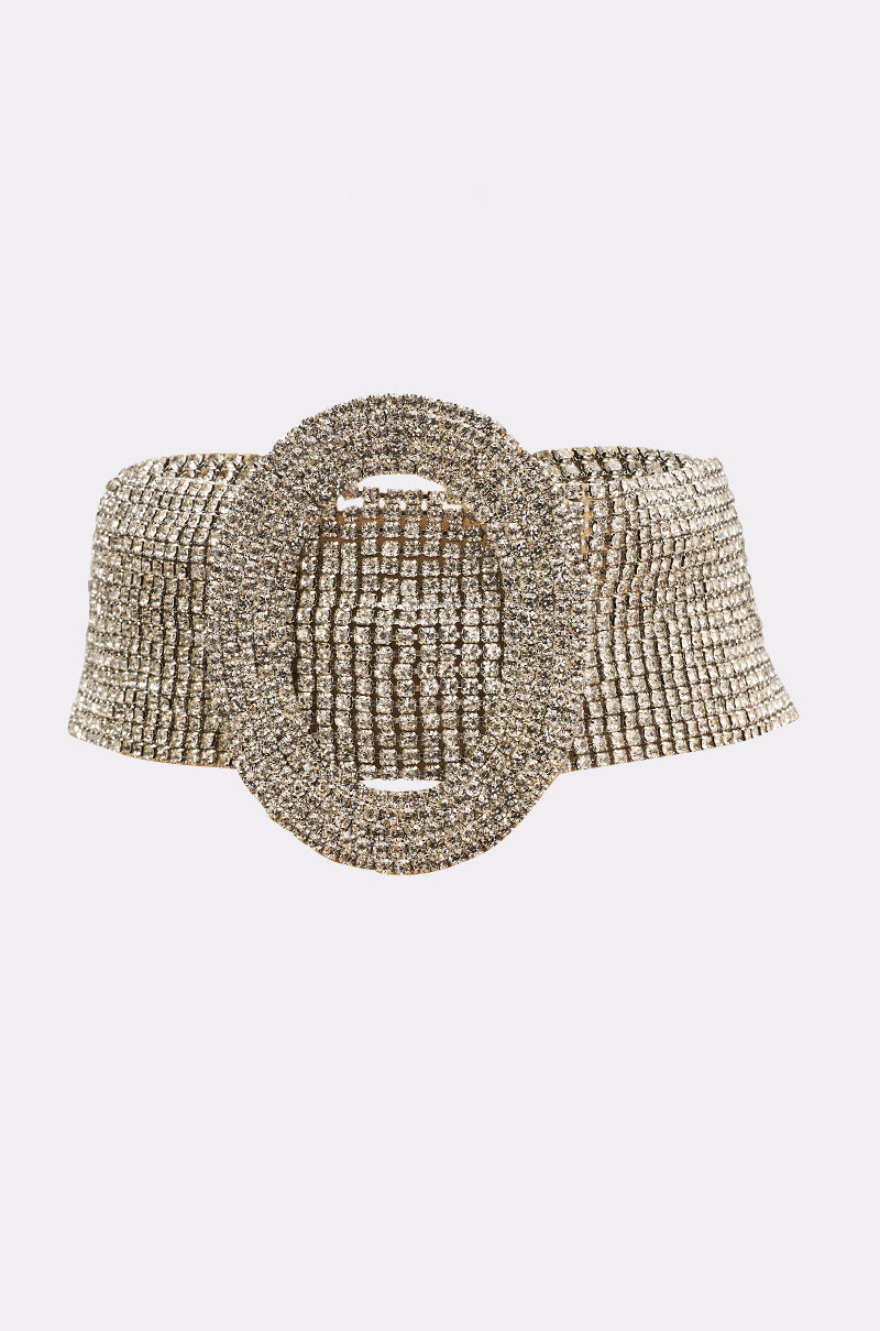 The KENDALL CHOKER stands out with a wide, sparkling gold band and a large oval rhinestone buckle, shown on a light background—ideal to pair with a rhinestone necklace for added glamour. 0