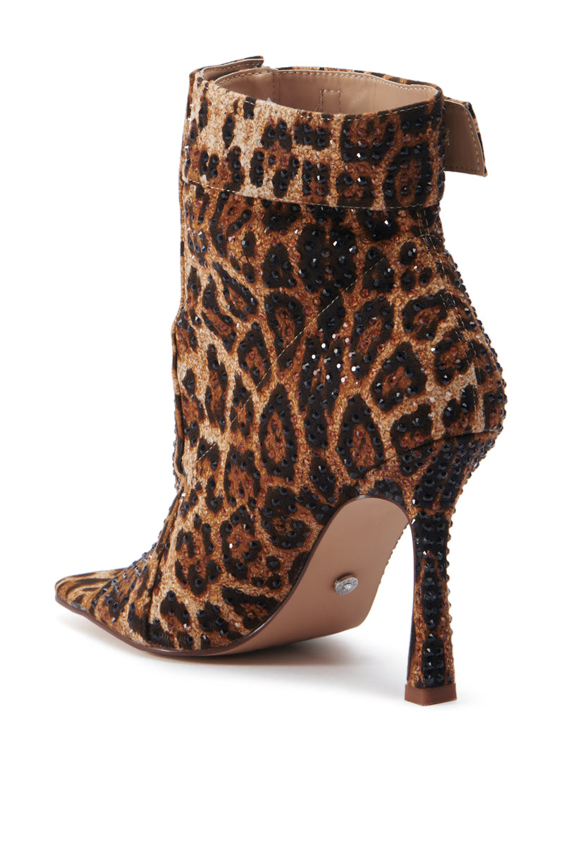 The AZALEA WANG NAILY CHEETAH BUTTON UP BOOTIE is a stylish cheetah-print bootie featuring a pointed toe and high stiletto heel. This boot is embellished with sparkling rhinestones that add a touch of glamour. Crafted from a mix of suede and glittery fabric, it includes a side zipper for easy wear and features a comfort cushion insole for added ease. 4