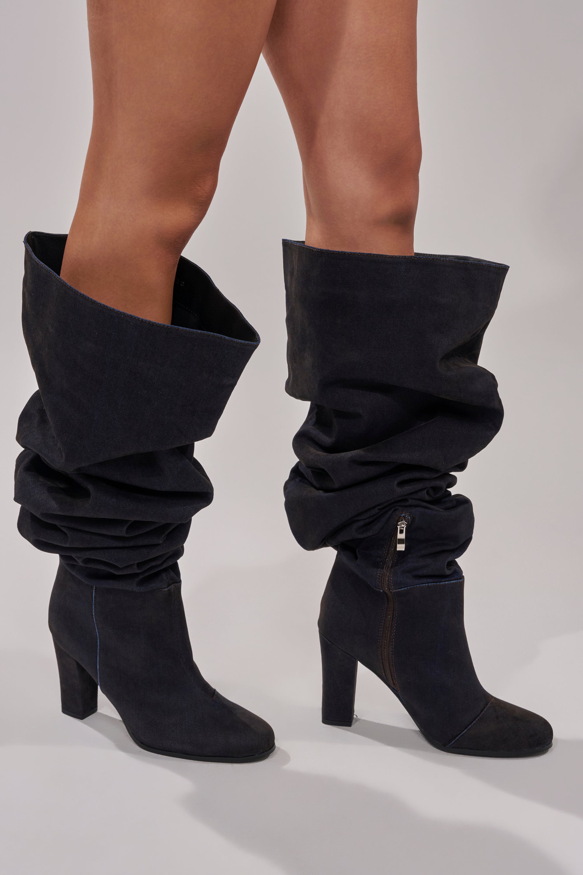 A person in AZALEA WANG NANETTE Black Denim Slouchy Black Round Toe Chunky Boots with side zippers stands against a light gray background.