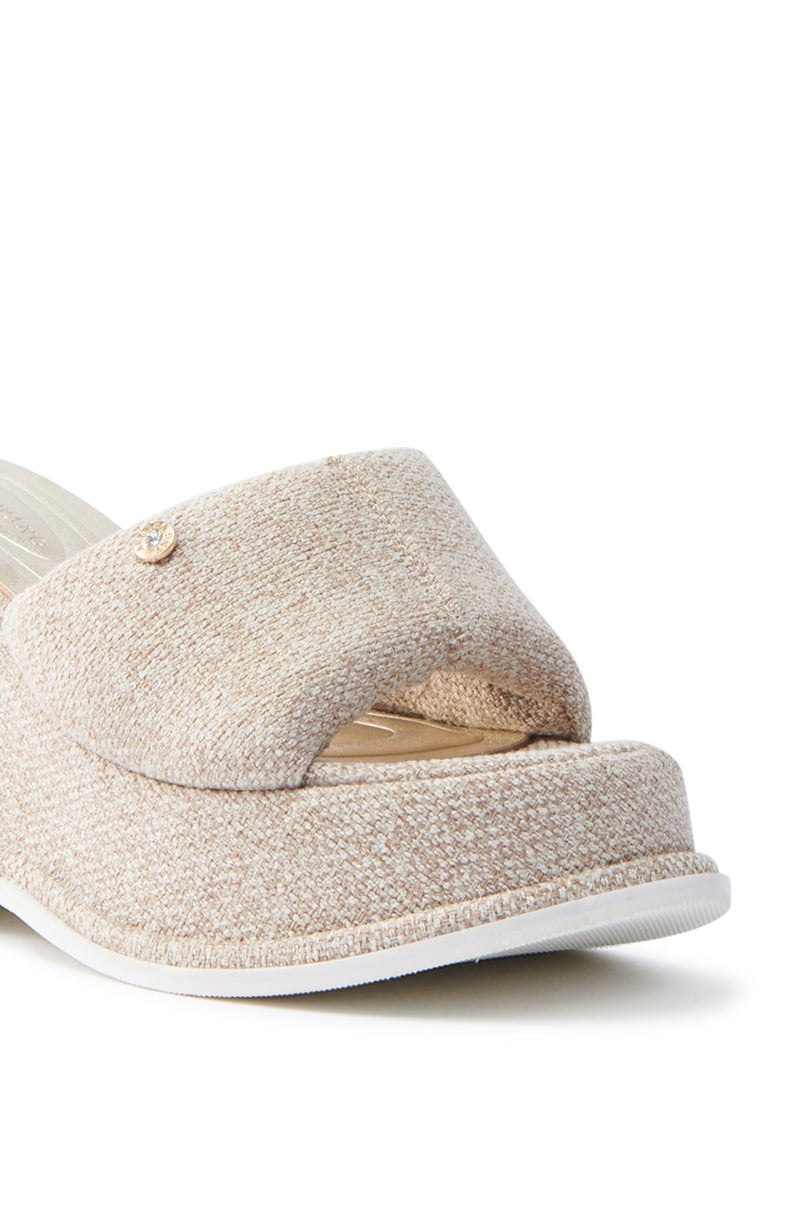 Close-up of the AZALEA WANG NATHALIA BEIGE NOVELTY FLATFORM SANDAL, featuring a textured fabric upper, open toe, and cushioned insole for enhanced comfort. The thick platform has a white bottom edge, while a metallic logo adds elegance.