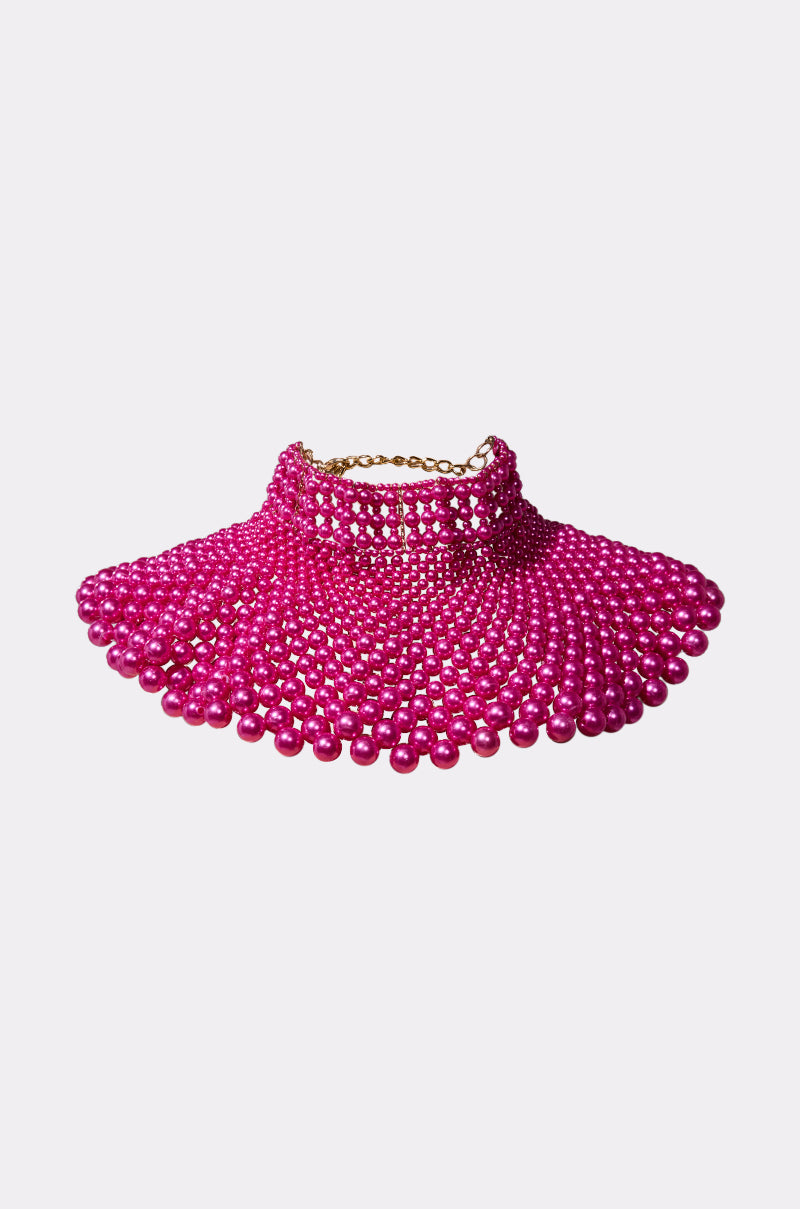 The FEEL MY POWER NECKLACE is a bold, wide statement necklace with hot pink beads in glossy rows and a flared, collar-like design, finished with a gold chain closure—perfect for standout style.
