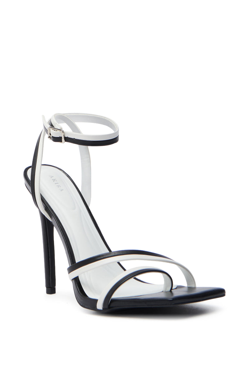 The AKIRA NEHARA BLACK AND WHITE STILETTO SANDAL is a sleek, modern shoe crafted from vegan leather, featuring a minimalist design with an open square toe, white ankle and toe straps, and a buckle closure.