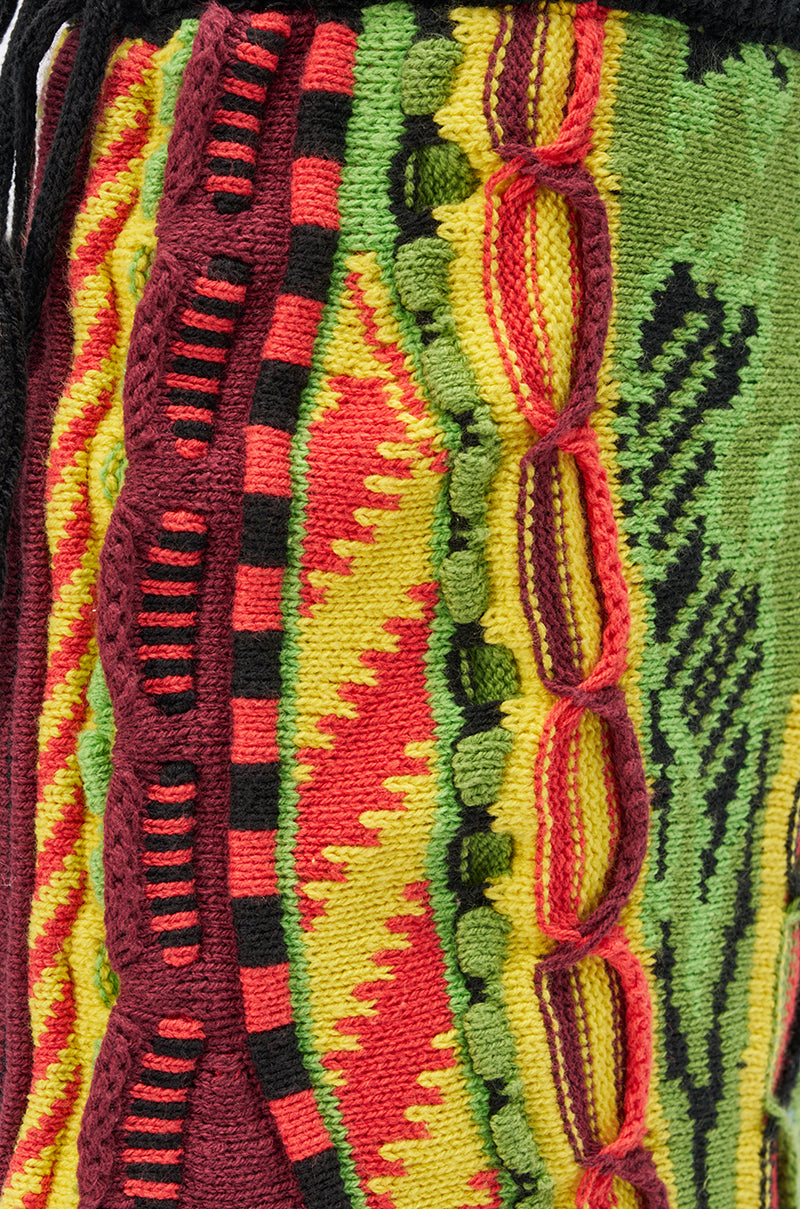 Close-up of a colorful knit fabric with wavy red, yellow, green, and black stripes—perfect to pair with the AKIRA GOLD NEIL SWEATER COMBAT BOOTIE for a bold and stylish look.