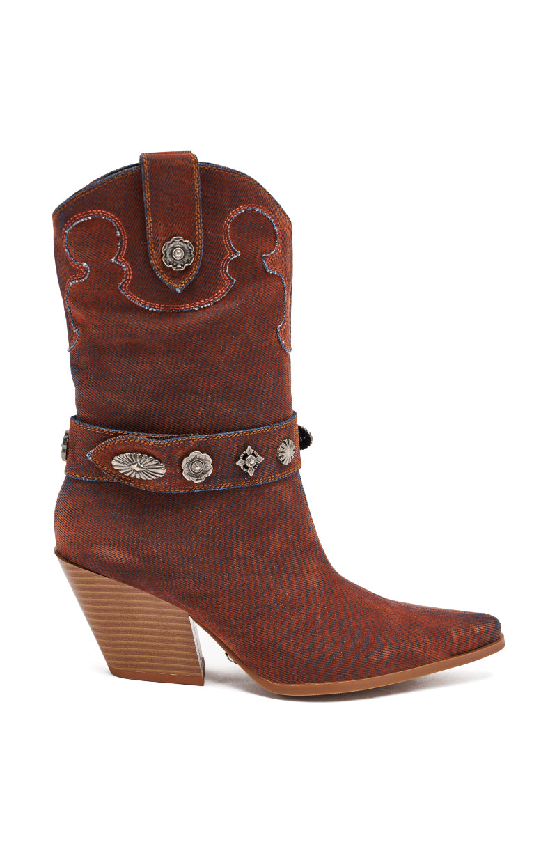 The AZALEA WANG NEITH BURNT ORANGE DENIM WESTERN BOOTIE is a mid-calf boot with a pointed toe, chunky heel, decorative stitching, and a strap featuring silver conchos and western-style metal accents.