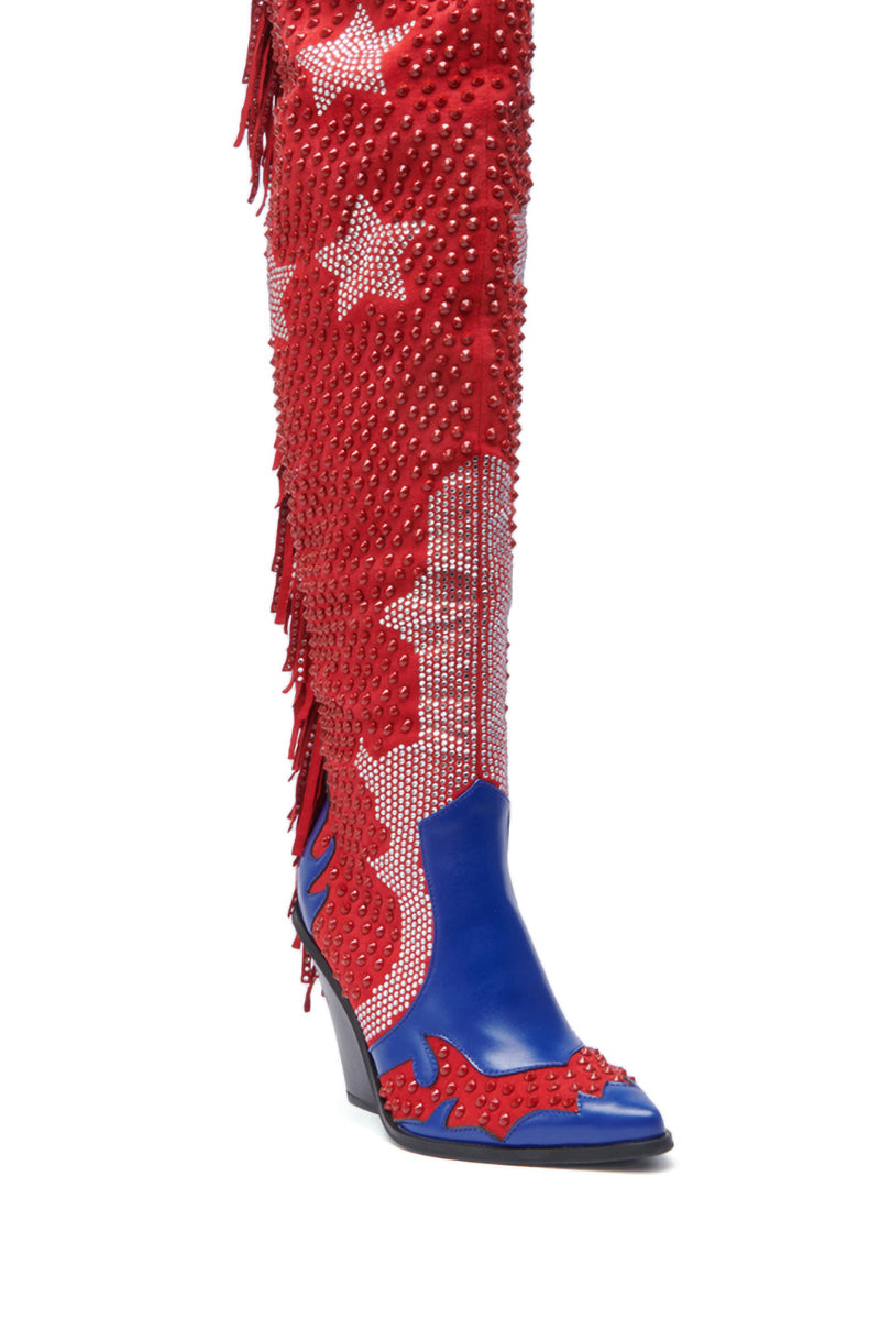 The AZALEA WANG NELLA BLUE MULTI WESTERN EMBELLISHED BOOT features a tall, pointed toe in red, white, and blue faux suede with white stars, red studs, fringe, rhinestones, flame-like blue accents, and a mid-height angled heel.