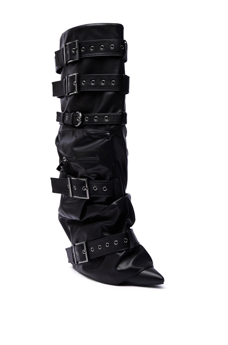 The AZALEA WANG NEMIANA BLACK BELT AND BUCKLES DETAIL BOOT is a black, knee-high boot featuring shiny faux leather, five wide buckle straps with silver hardware, a pointed toe, and a slightly slouched design.
