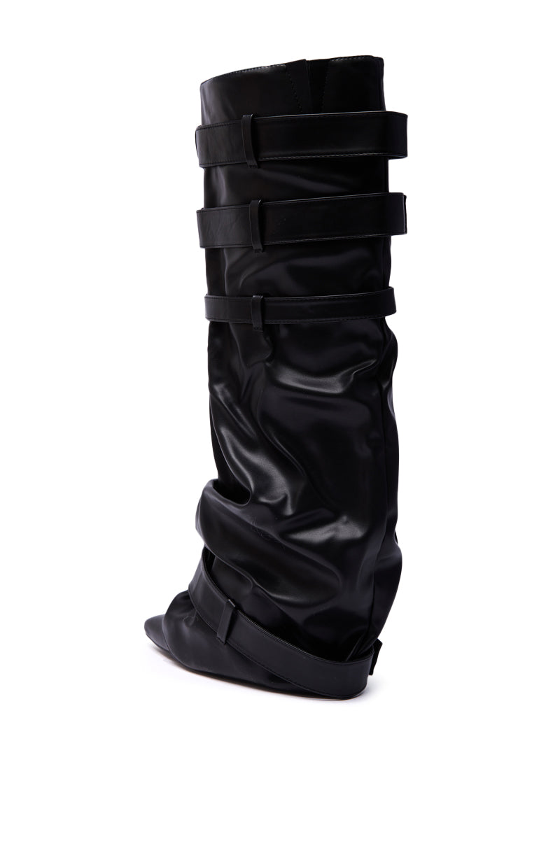 The AZALEA WANG NEMIANA BLACK BELT AND BUCKLES DETAIL BOOT is a black, knee-high boot crafted from glossy ruched faux leather, featuring four horizontal straps and a pointed toe, displayed against a white background.