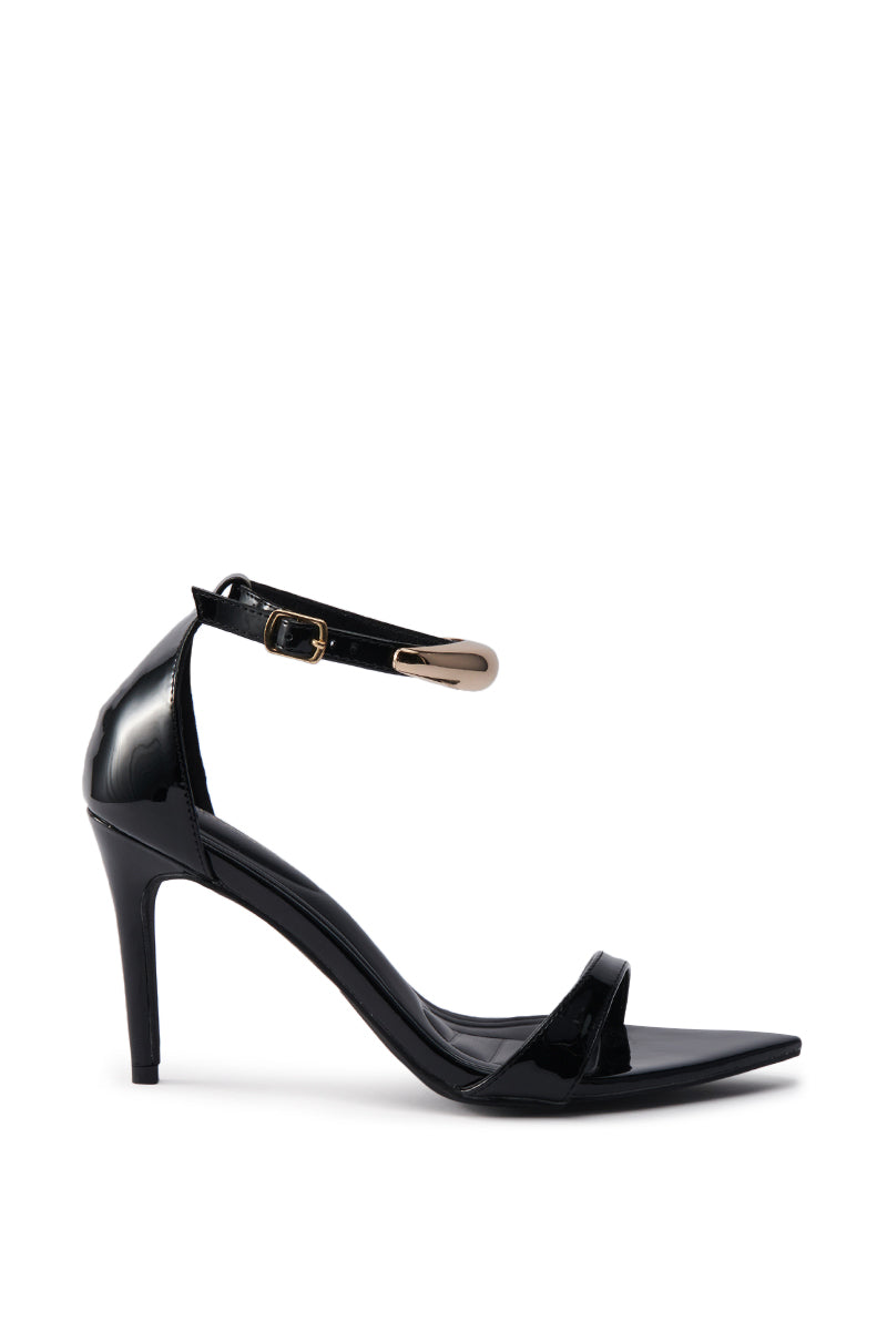 The AKIRA NEMTI BLACK STILETTO SANDAL is a black patent leather heel with a pointed toe, adjustable ankle strap with gold buckle, and single front strap, shown in a side view on a white background.