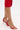 A person wearing AZALEA WANG NEMTI red PU sandals with gold embellishment and red ruffled pants stands on a white surface.