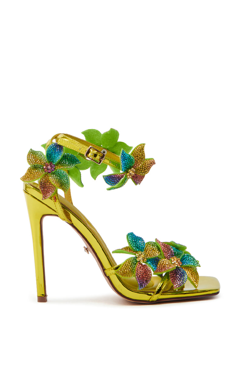 The AZALEA WANG NERIYA sandal features a shiny gold finish with rhinestone flower stilettos and colorful floral decorations on the strap and ankle, secured by a buckle.
