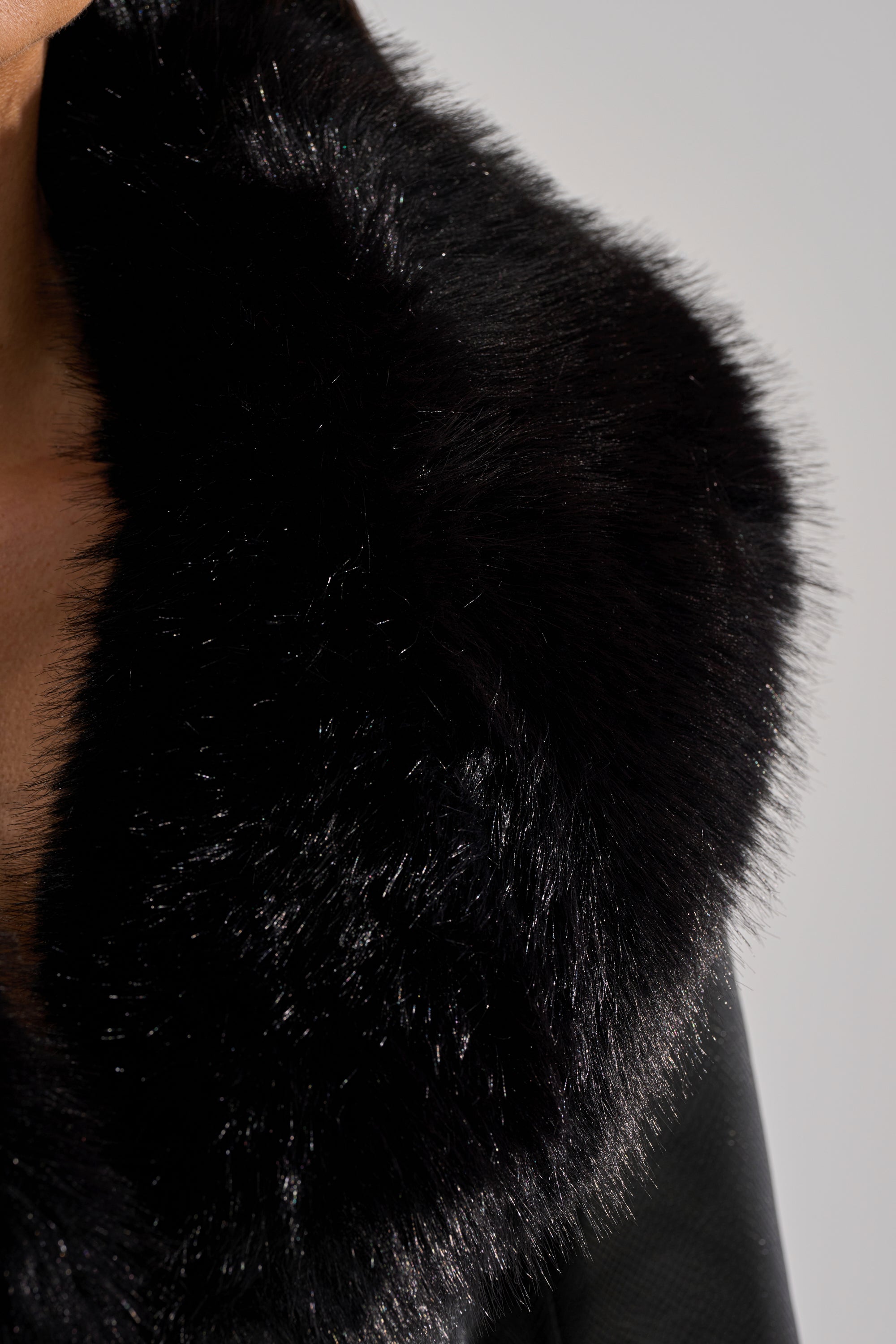 Close-up of a person wearing the GISELE CROP MOTO BLAZER, featuring a large, fluffy black collar. Only part of the neck, shoulder, and textured faux fur are visible against a neutral background.