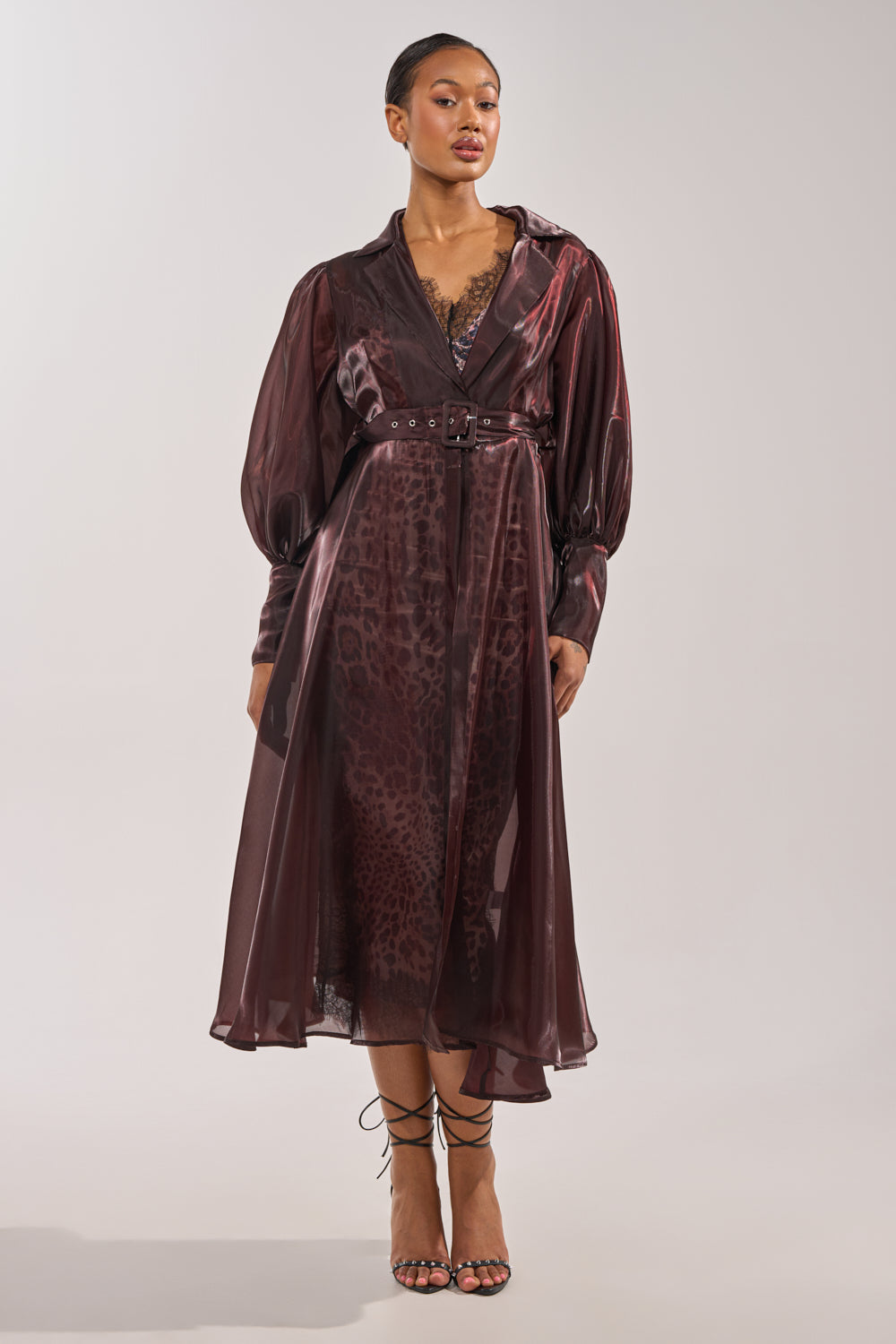 A woman models a sheer, belted burgundy leopard midi dress with lace trim, styled under the PRETTY LIL THING ORGANZA TRENCH in brown and finished with strappy black heels. 4