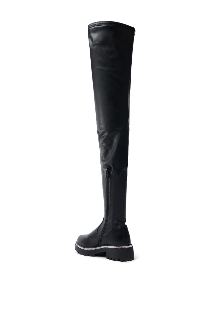 Displayed on a white background is the sleek AZALEA WANG NEWRULES RHINESTONE STRETCH PU FLAT BOOT, a black over-the-knee design with a textured sole and inner zipper. The boot stands upright, highlighting its stylish features.