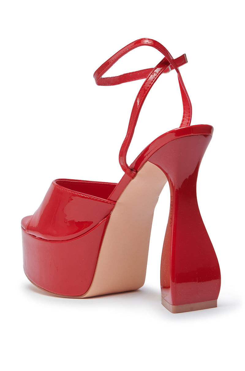 The AZALEA WANG NEWTON RED CHUNKY PLATFORM SANDAL features shiny red faux patent leather, an ankle strap, thick beige sole, and a uniquely sculpted flared chunky heel for standout style.