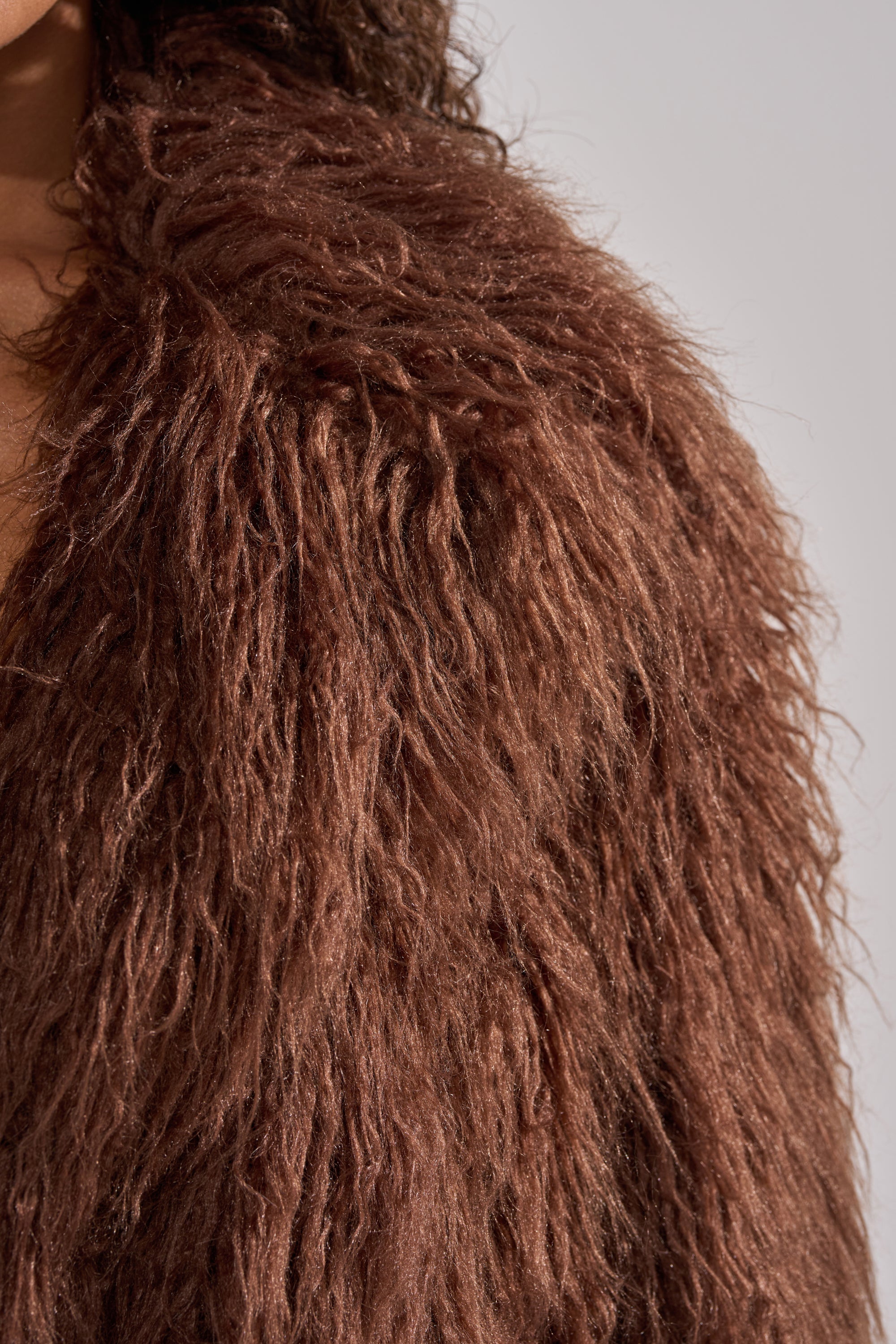 Close-up of a person wearing the SHORT N SWEET FAUX FUR COAT in chocolate, highlighting the soft, textured faux fur material against a neutral background.