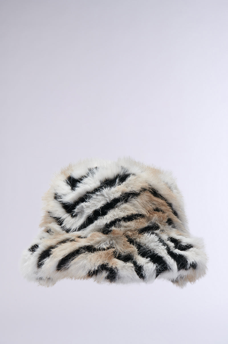 Introducing the Wilder Faux Fur Bucket Hat, a soft and plush accessory featuring a fluffy design with tiger stripes in black, white, and tan hues, beautifully set against a plain light gray backdrop. 2